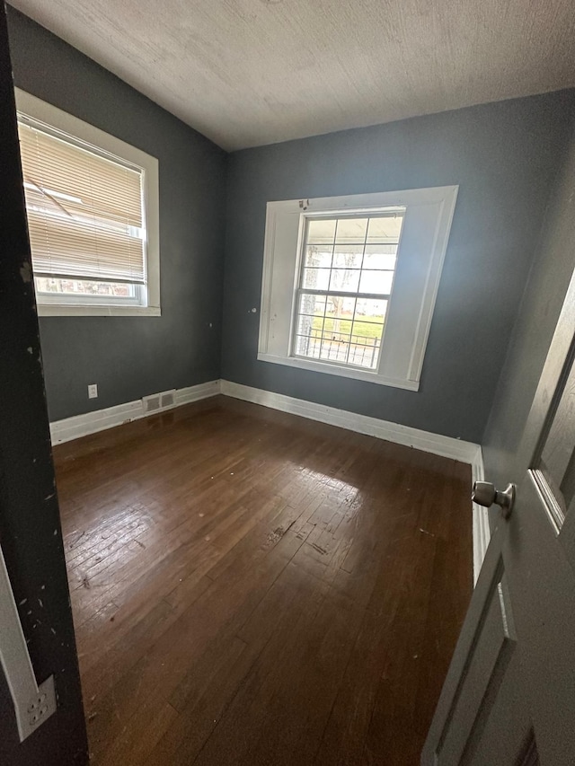 spare room with a textured ceiling and dark hardwood / wood-style floors