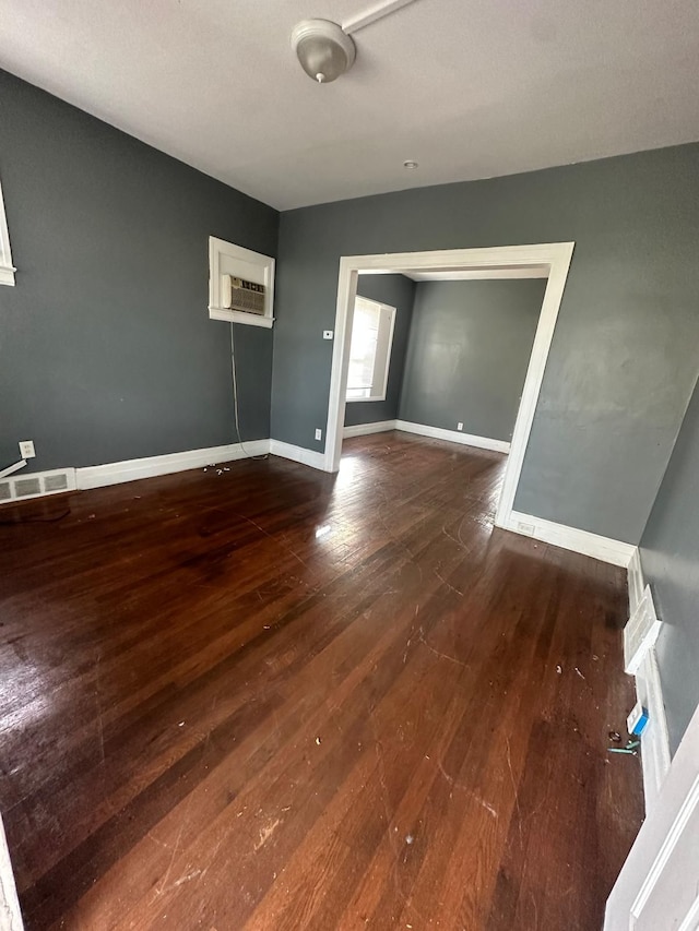 spare room with dark hardwood / wood-style flooring and an AC wall unit