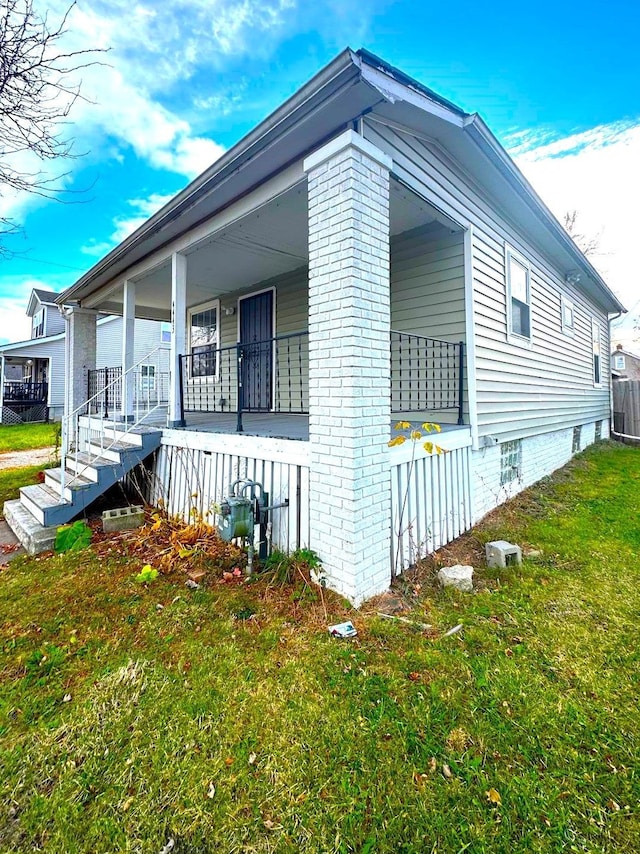 view of side of home with covered porch and a yard