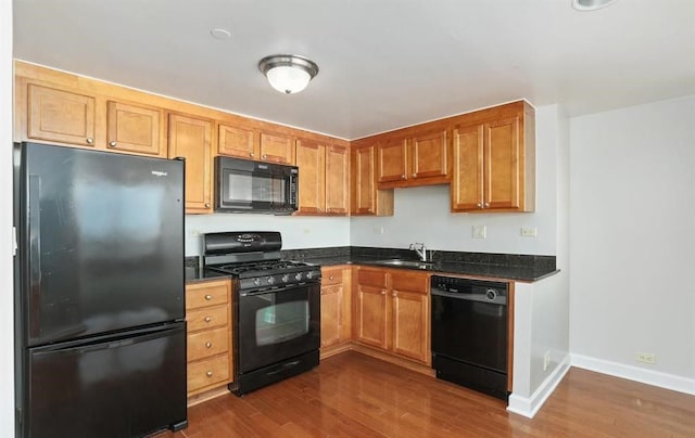 kitchen featuring dark wood-type flooring, black appliances, and sink