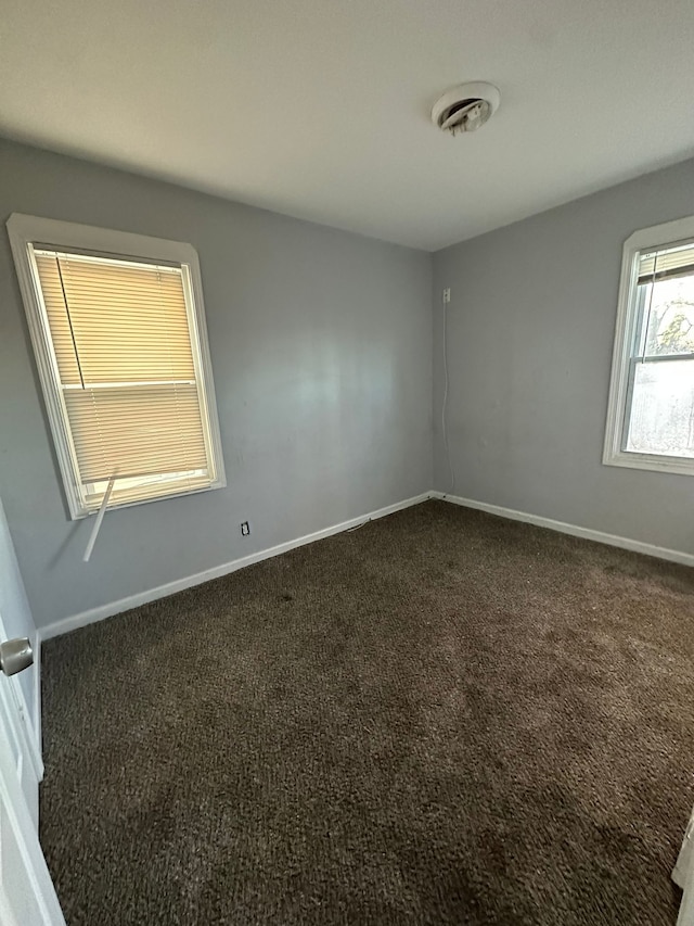 spare room featuring dark colored carpet