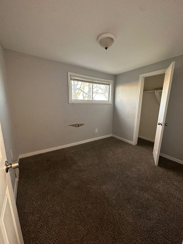 unfurnished bedroom with dark colored carpet and a textured ceiling