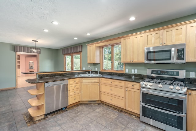 kitchen featuring sink, light brown cabinets, kitchen peninsula, pendant lighting, and stainless steel appliances