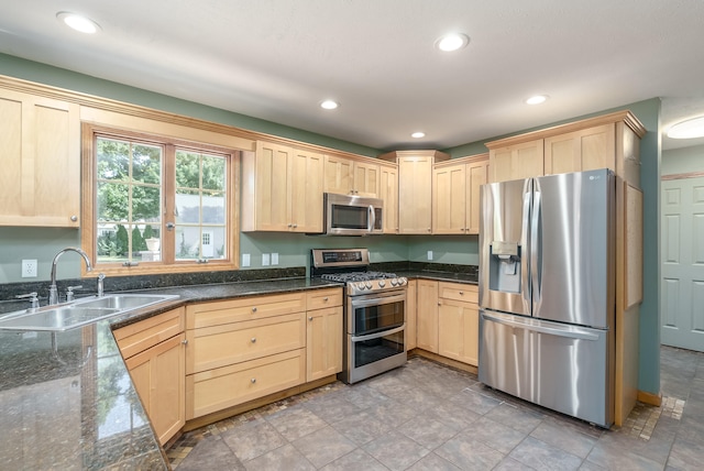 kitchen featuring dark stone countertops, sink, stainless steel appliances, and light brown cabinets