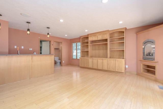 unfurnished living room with sink, built in features, and light wood-type flooring