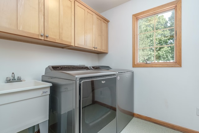 washroom with cabinets, washer and clothes dryer, and sink