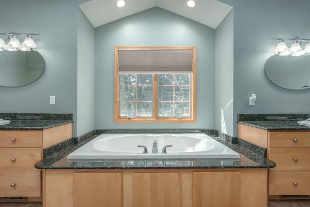 bathroom with vaulted ceiling, a bathing tub, and vanity