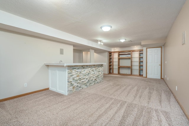 interior space featuring indoor bar, carpet, and a textured ceiling