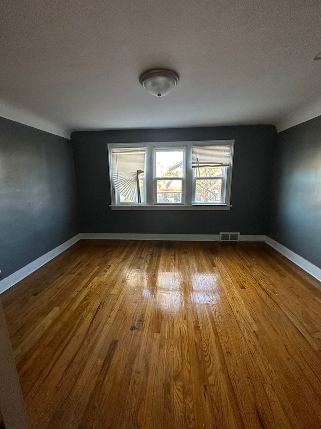 empty room featuring wood-type flooring and a textured ceiling