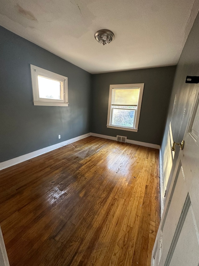 unfurnished room with a textured ceiling, light hardwood / wood-style floors, and plenty of natural light