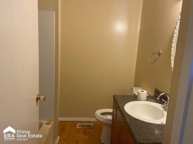 bathroom featuring vanity, a bathtub, toilet, and wood-type flooring