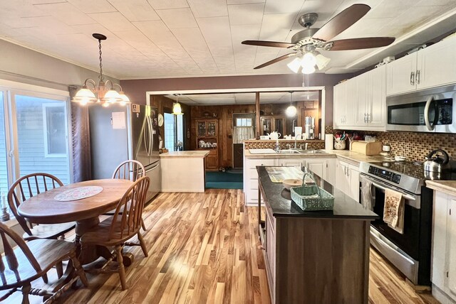 5376 Circle Dr, Reading, MI 49274 - kitchen featuring appliances with stainless steel finishes, a sink, light wood finished floors, white cabinetry, and a peninsula