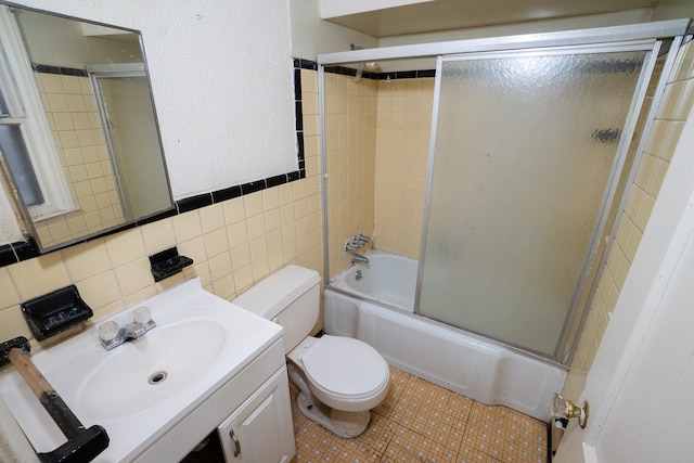 full bathroom with vanity, toilet, shower / bath combination with glass door, and tile walls