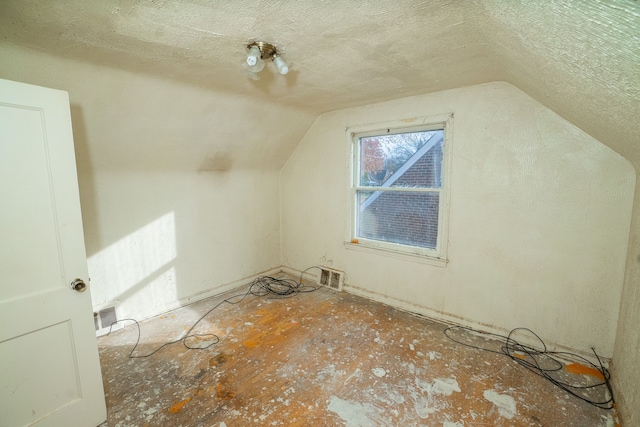 additional living space featuring a textured ceiling and vaulted ceiling