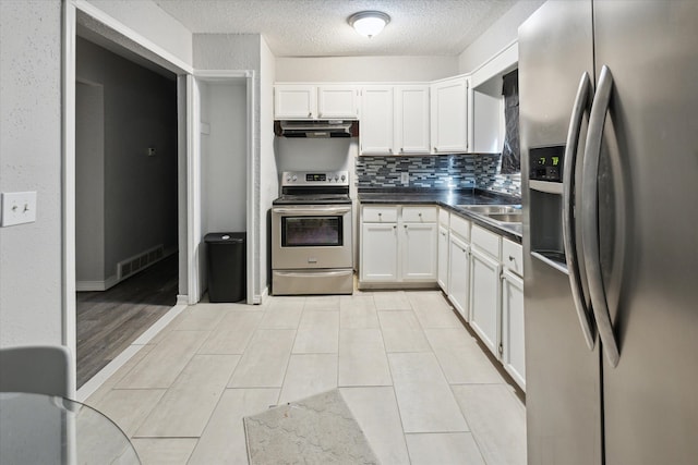 kitchen featuring tasteful backsplash, a textured ceiling, stainless steel appliances, light hardwood / wood-style flooring, and white cabinetry