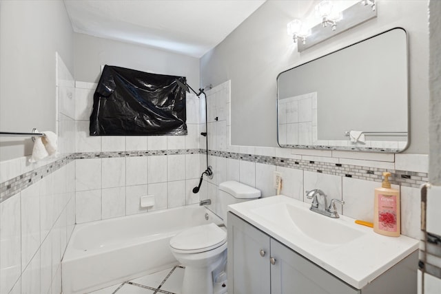 full bathroom featuring vanity, tiled shower / bath, tile patterned flooring, toilet, and tile walls