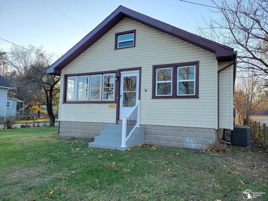 bungalow-style home with a front yard and cooling unit