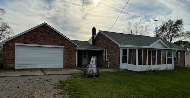 back of property featuring a yard, a garage, and a sunroom