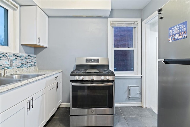 kitchen with white cabinetry, sink, tasteful backsplash, dark tile patterned flooring, and appliances with stainless steel finishes