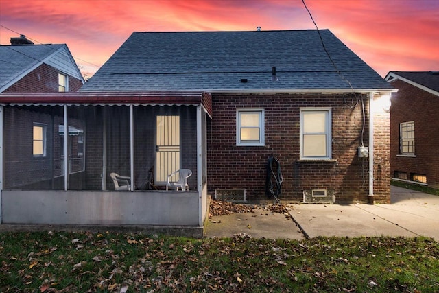 back house at dusk featuring a sunroom