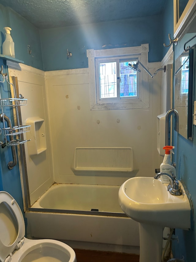 bathroom featuring toilet, a textured ceiling, and shower / washtub combination