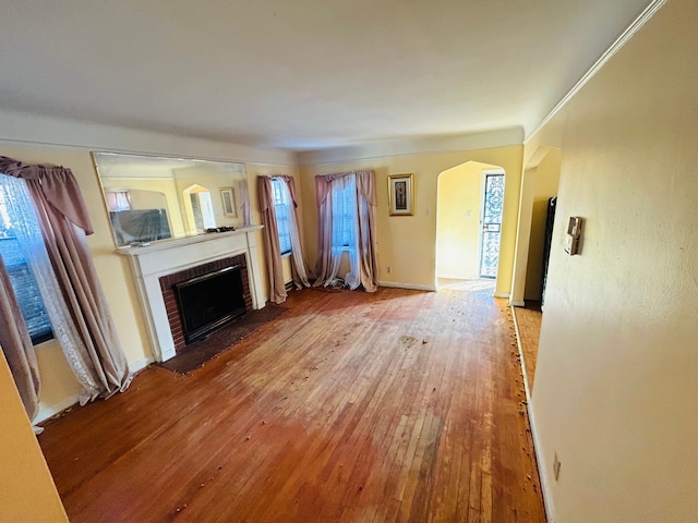 unfurnished living room with a fireplace, wood-type flooring, and crown molding