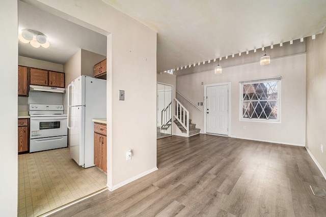 kitchen featuring pendant lighting, light wood-type flooring, and white appliances