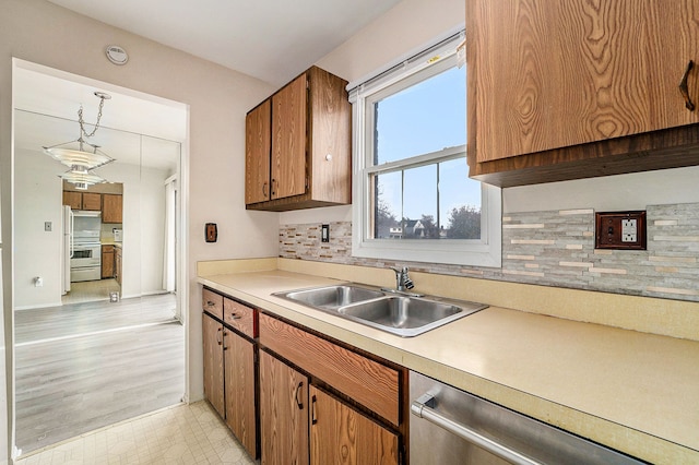 kitchen featuring dishwasher, backsplash, white range, sink, and light hardwood / wood-style floors