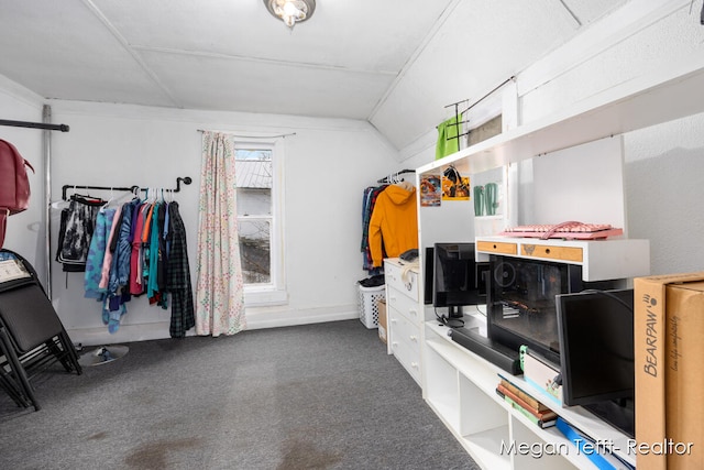 walk in closet with dark carpet and lofted ceiling