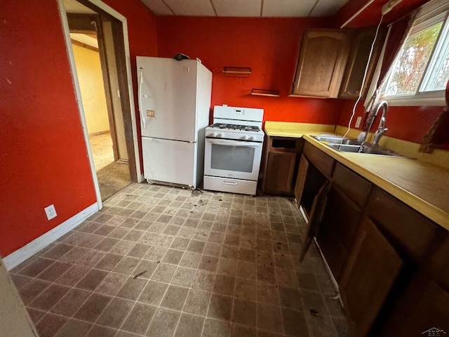 kitchen with a drop ceiling, white appliances, and sink