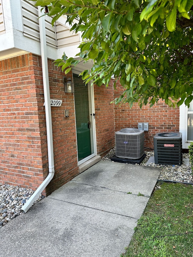 property entrance with brick siding and central AC unit