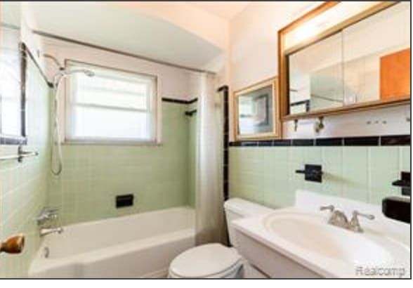 full bathroom featuring vanity, toilet, tile walls, and shower / tub combo with curtain