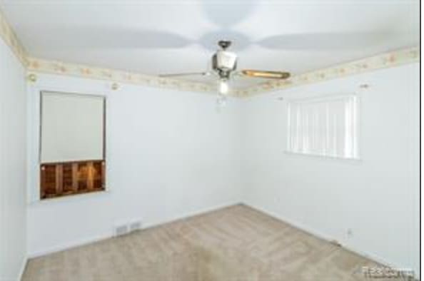 carpeted spare room featuring ceiling fan