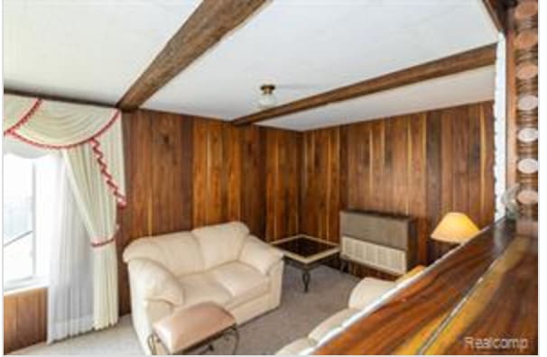 living room with beamed ceiling and wooden walls