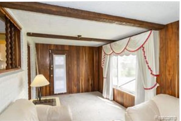 living room featuring beam ceiling, wood walls, and a healthy amount of sunlight