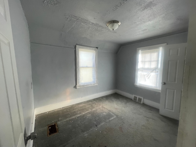 carpeted empty room with a textured ceiling and vaulted ceiling