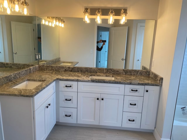 full bathroom with double vanity, a bathtub, and tile patterned flooring