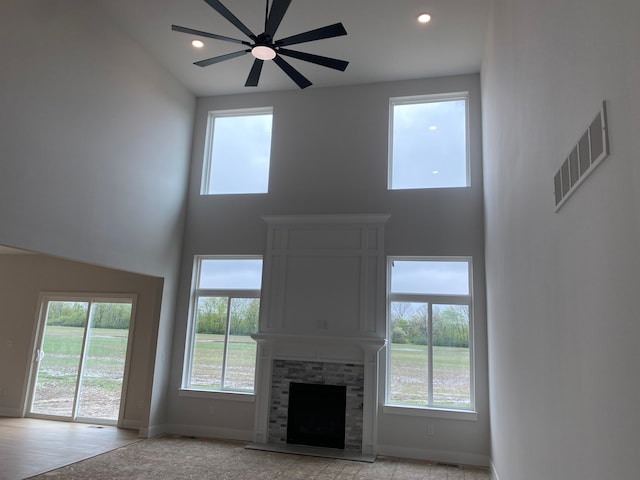 32627 Adam Brown Dr, Rockwood, MI 48173 - unfurnished living room with a towering ceiling, baseboards, ceiling fan, a fireplace with raised hearth, and recessed lighting