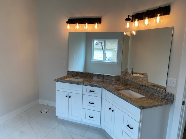 bathroom with double vanity, marble look tiles, and baseboards