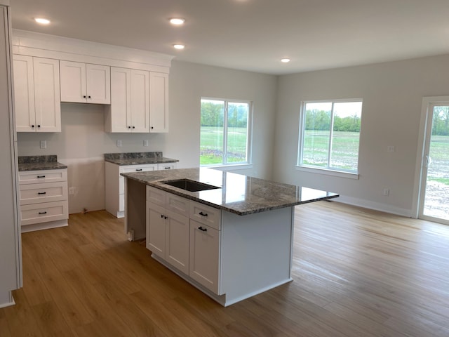 32627 Adam Brown Dr, Rockwood, MI 48173 - kitchen featuring light wood finished floors, dark stone counters, plenty of natural light, white cabinets, and recessed lighting