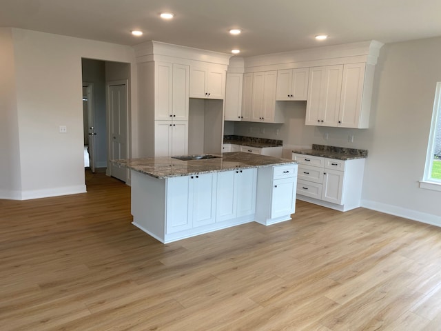 kitchen with baseboards, white cabinets, light wood-type flooring, and recessed lighting