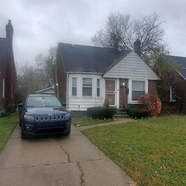 bungalow featuring brick siding, a front lawn, and roof with shingles