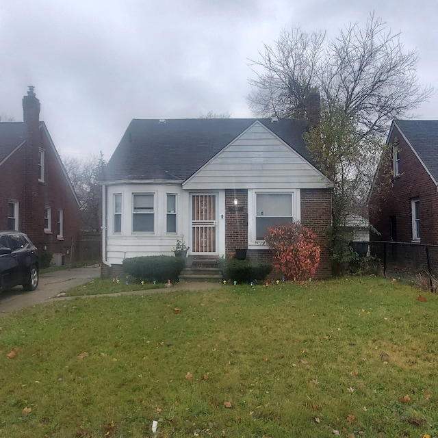 bungalow with brick siding, fence, and a front yard