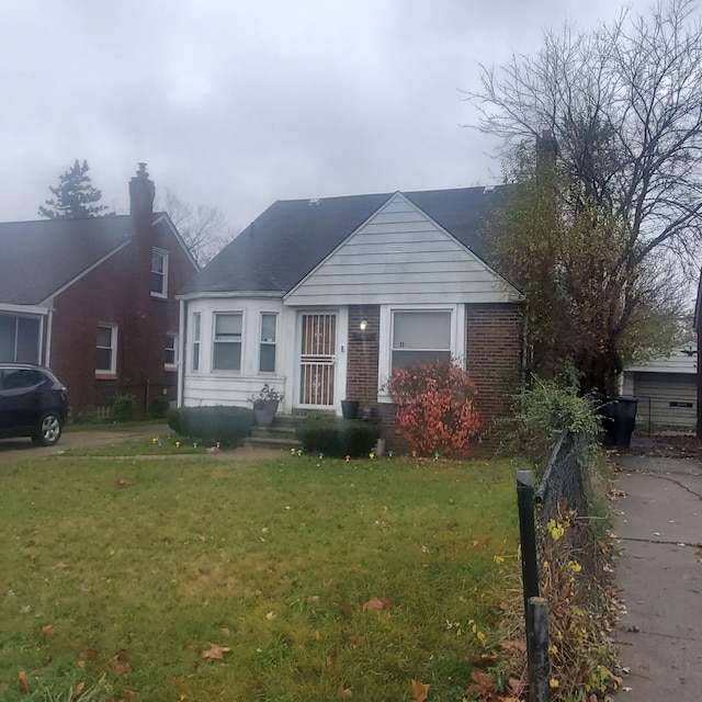 bungalow with fence, a front lawn, and brick siding