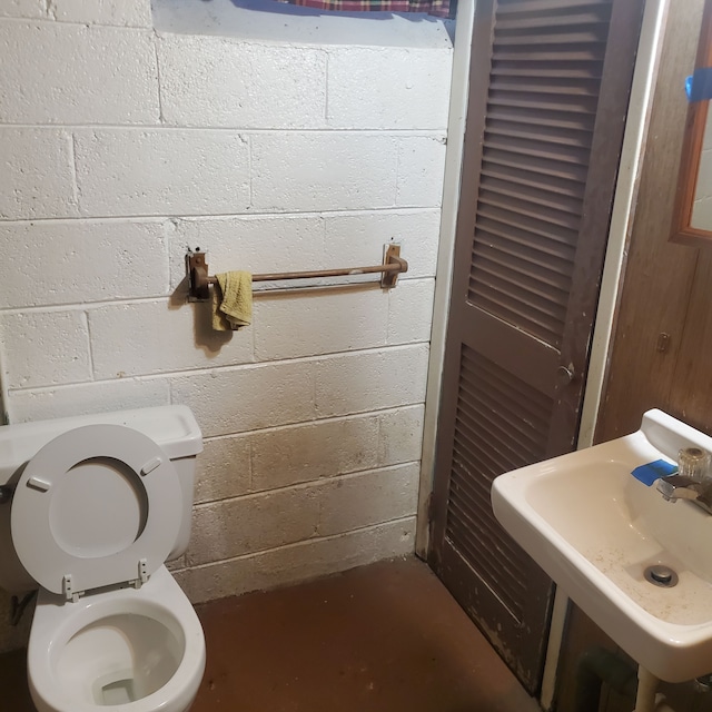 bathroom with concrete floors, a sink, and toilet