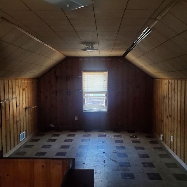 bonus room featuring lofted ceiling, visible vents, wooden walls, and tile patterned floors