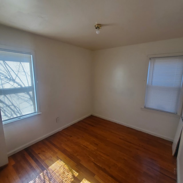 unfurnished room with baseboards and wood finished floors