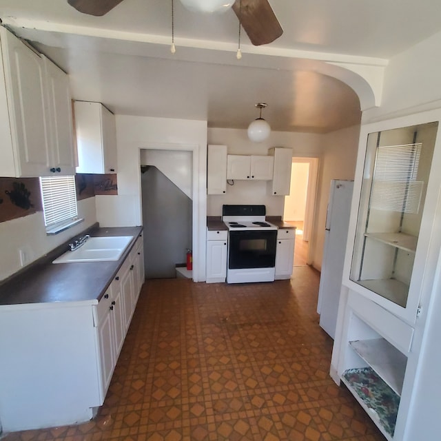 kitchen featuring white appliances, arched walkways, dark floors, white cabinetry, and a sink