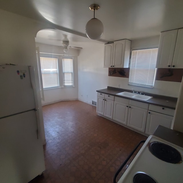 kitchen featuring dark countertops, white appliances, visible vents, and a sink