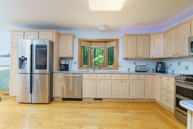 kitchen featuring decorative backsplash, sink, light wood-type flooring, and stainless steel appliances